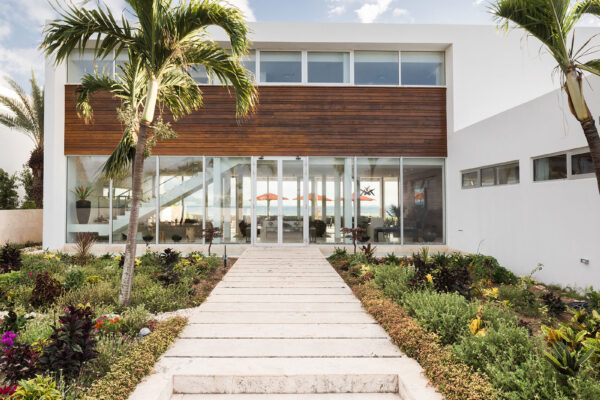 Exterior view of Champagne Shores Villa, featuring modern architecture, large windows, and a beautifully landscaped garden with palm trees.