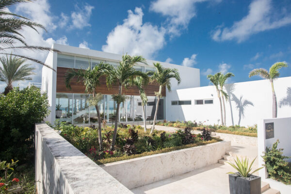 Exterior view of Champagne Shores Villa, featuring modern architecture, large windows, and a beautifully landscaped garden with palm trees.