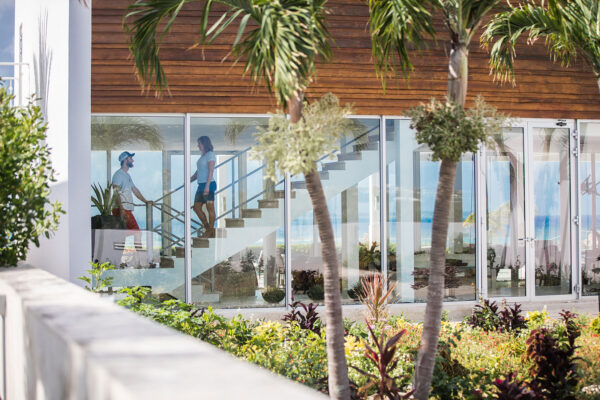 Exterior view of Champagne Shores Villa, featuring modern architecture, large windows, and a beautifully landscaped garden with palm trees.