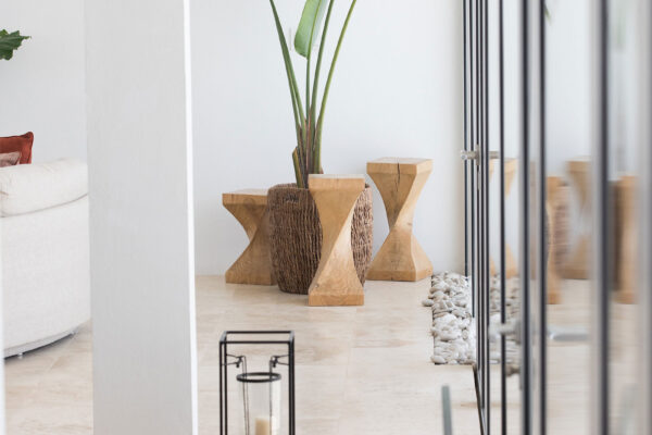 Close-up of the living area at Champagne Shores Villa, featuring a stylish arrangement with wooden stools, a tall plant, and modern lanterns on a tiled floor.