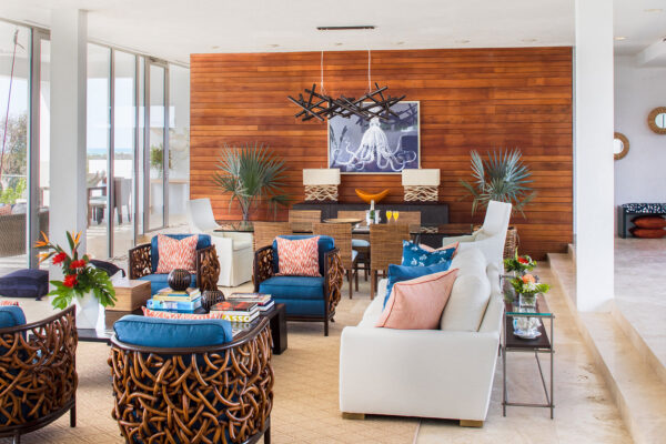 Luxurious living area at Champagne Shores Villa with stylish wicker chairs, colorful cushions, and modern decor. The space features a dining area, large windows with ocean views, and elegant lighting
