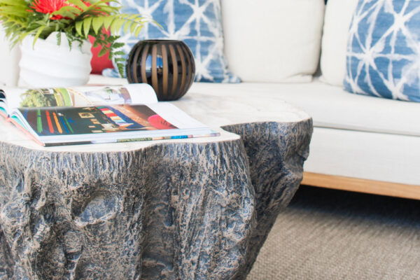 Close-up of the primary suite at Champagne Shores Villa, featuring a rustic wooden coffee table with a flower arrangement and magazine, and a cozy seating area with blue and white pillows.